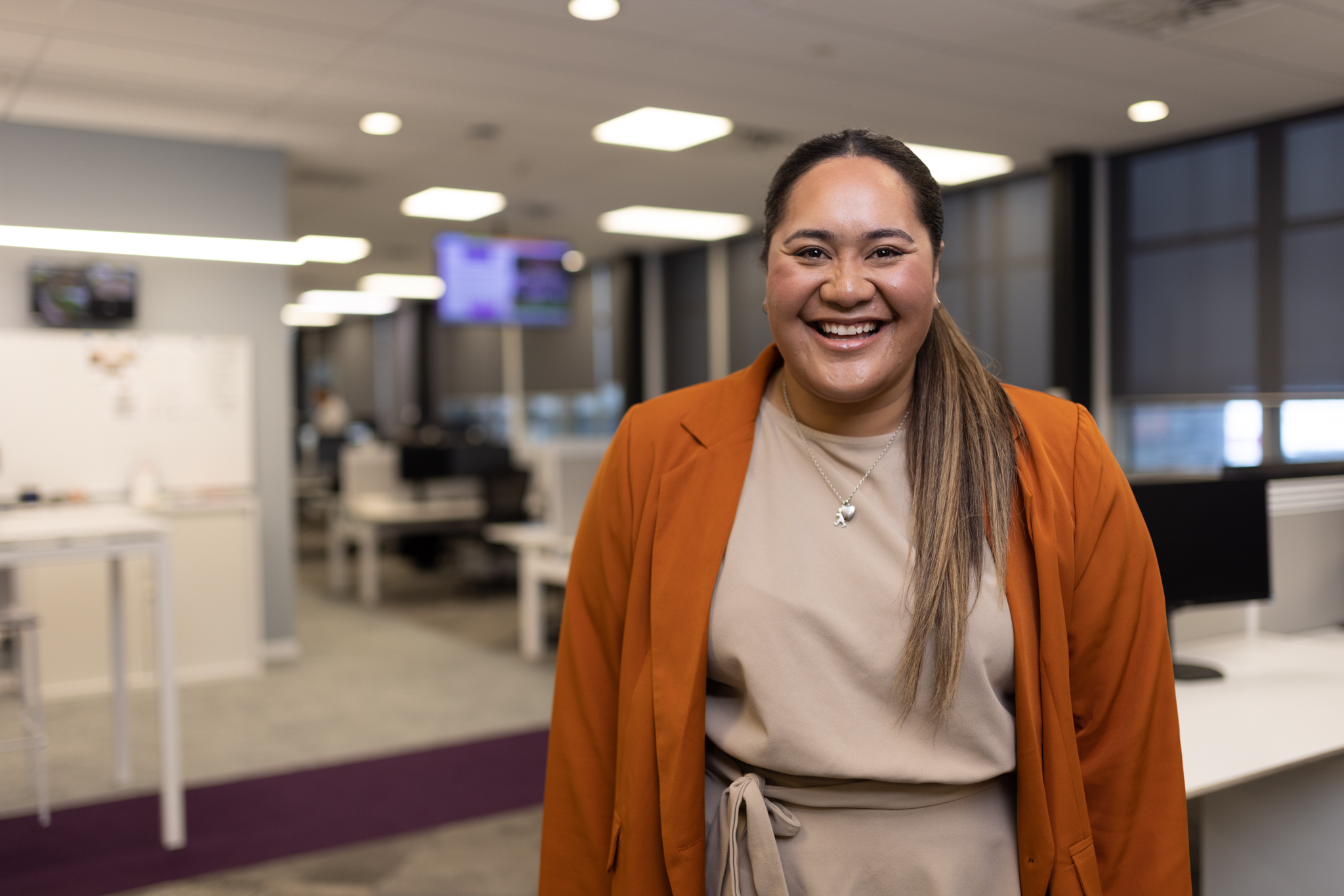Operations Adviser stands smiling in Electronic Monitoring Operations Office